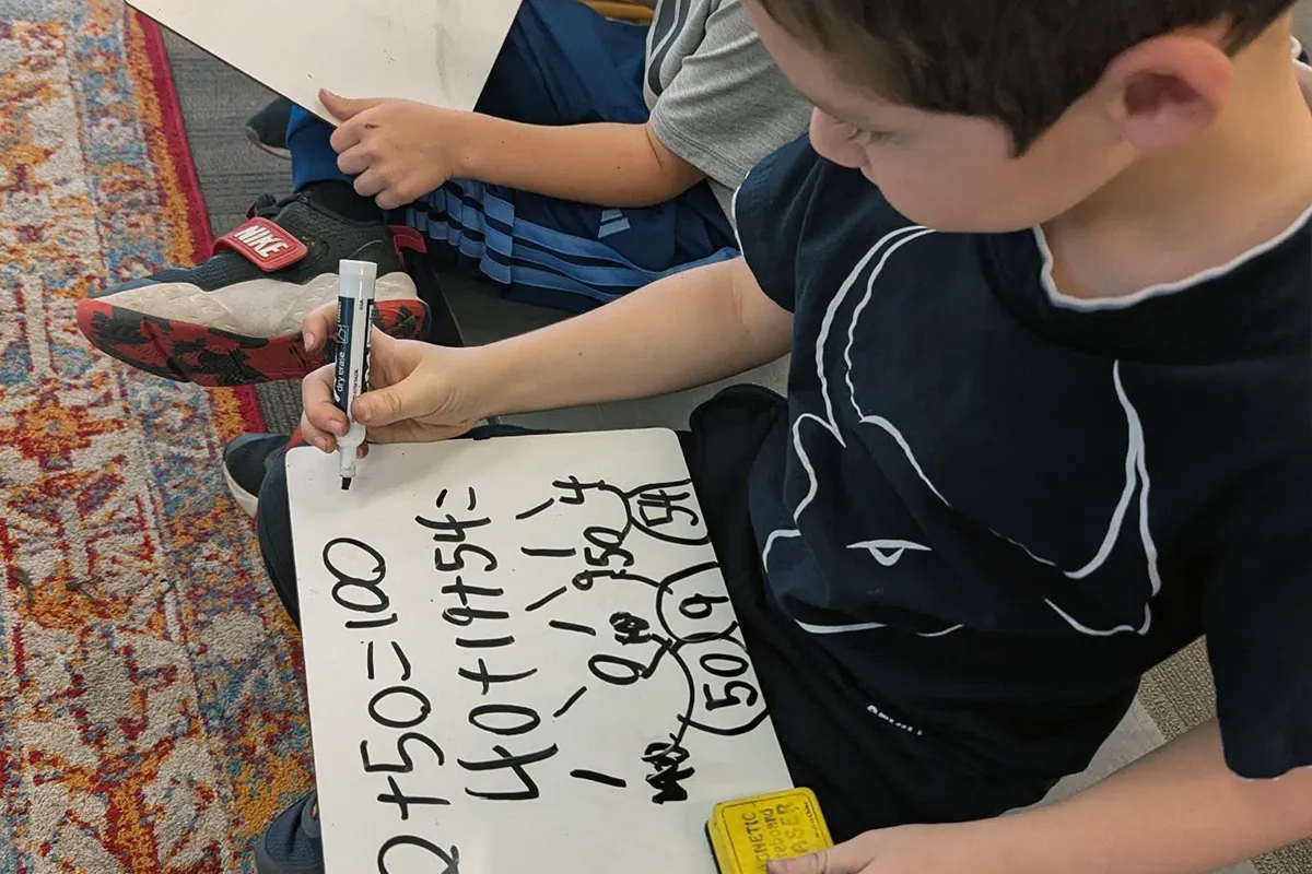 summit-elementary-mathematical-thinking Summit elementary student using a whiteboard to work through a math problem.
