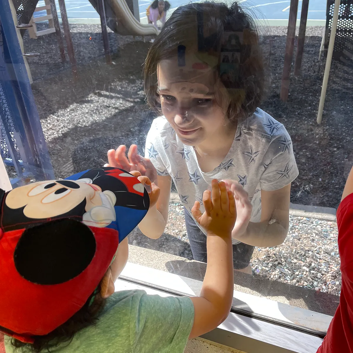 Preschool students connecting with their Big Buddies through a classroom window at Summit School.
