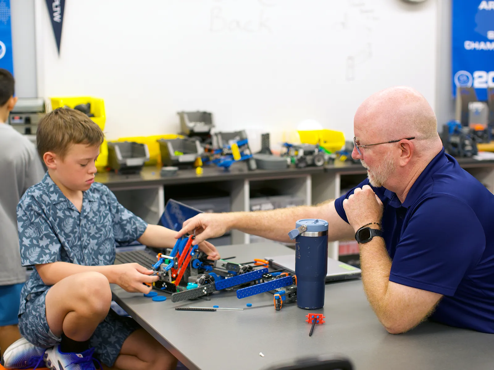 summit-school-teacher-student-robotics Summit School teacher working one-on-one with a student during robotics.