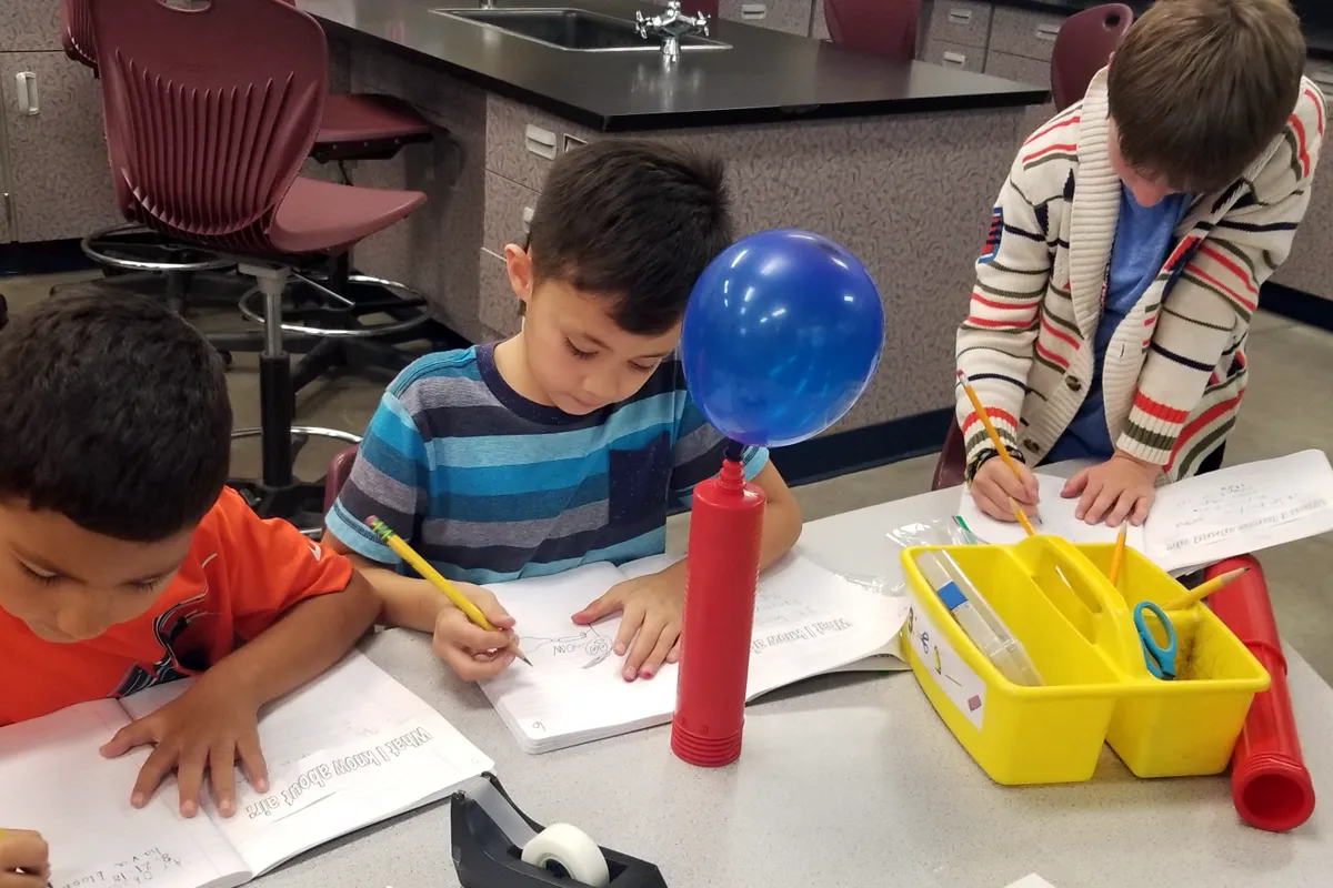 summit-elementary-science-balloon-experiment Elementary students conducting a balloon experiment and recording observations during science class at Summit School.