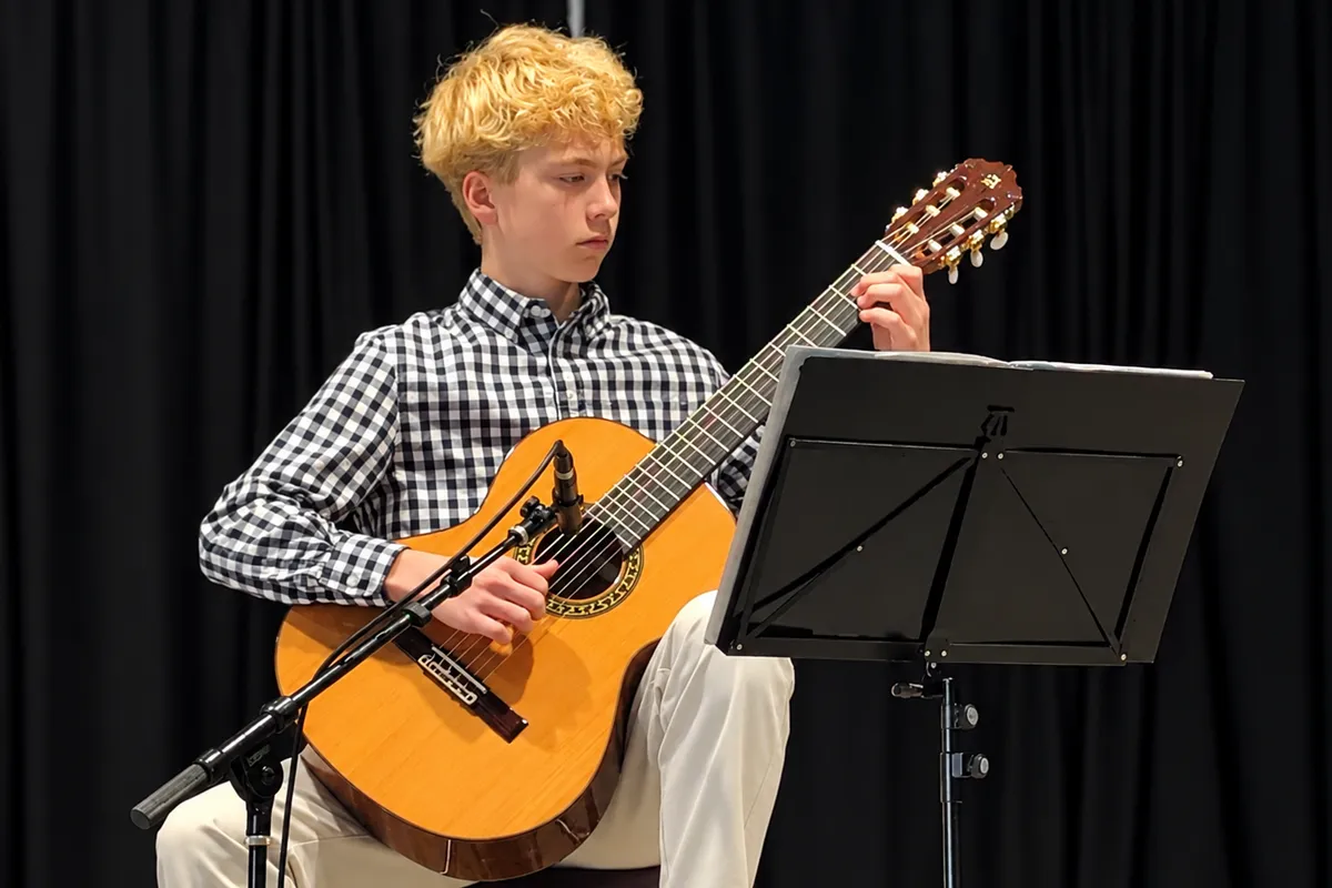 summit-middle-school-music-performance-elective Summit Middle School student performing classical guitar on stage.