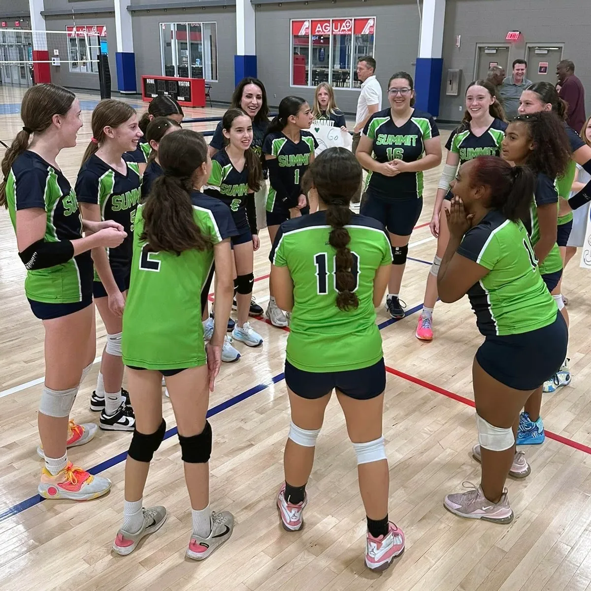 Summit Middle School volleyball players gather with their coach during a competitive match.