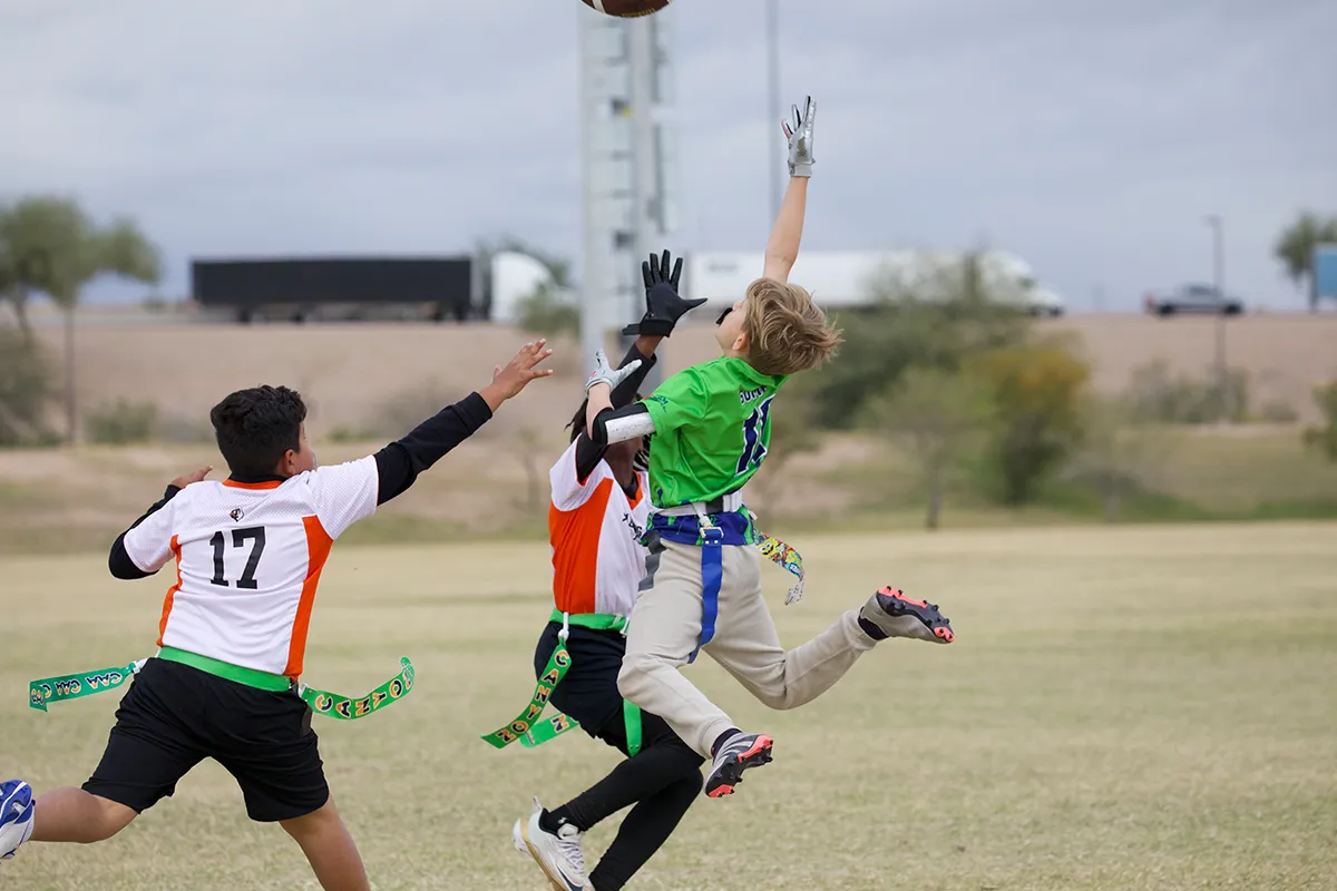 summit-school-flag-football Summit student leaping to catch a pass during a flag football game.