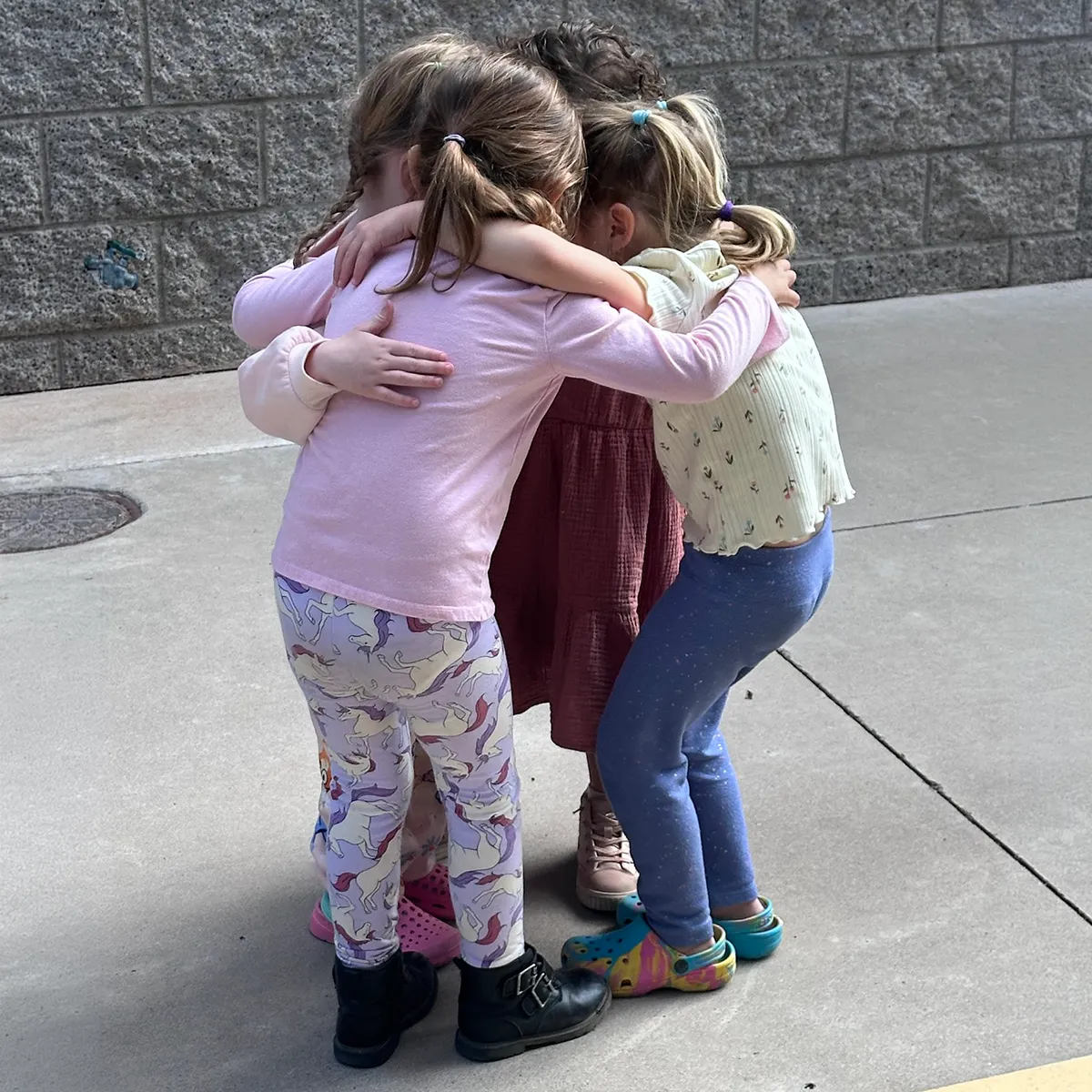 summit-school-student-connection-belonging Young Summit students sharing a group hug on campus.