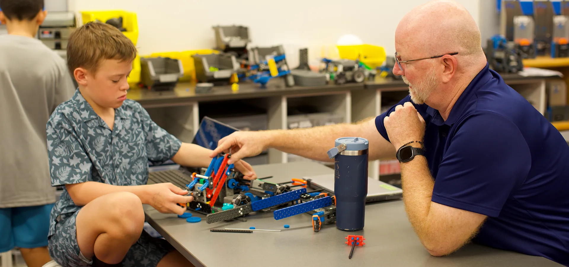 Summit School student working on a VEX robotics project with guidance from a Cybercat Robotics mentor.