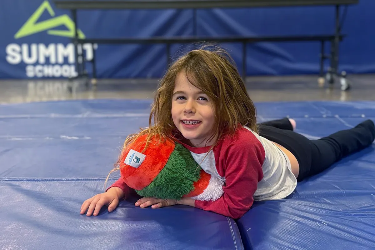 summit-school-time-to-unwind-extended-day Student relaxing with a stuffed animal during time to unwind at Summit School.